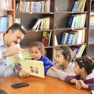 Mohammad, a Syrian refugee, reading to children in Azarq camp, Jordan